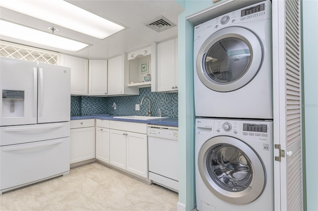 clothes washing area with stacked washer / drying machine and sink