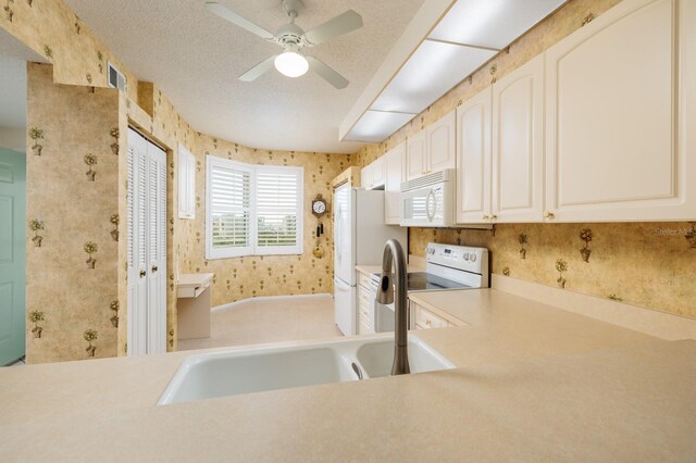 kitchen with white cabinetry, sink, white appliances, ceiling fan, and a textured ceiling