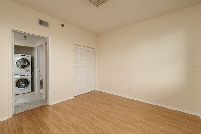 interior space with a closet, stacked washer / drying machine, and light hardwood / wood-style flooring