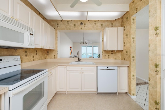 kitchen with white appliances, sink, white cabinetry, decorative light fixtures, and ceiling fan with notable chandelier