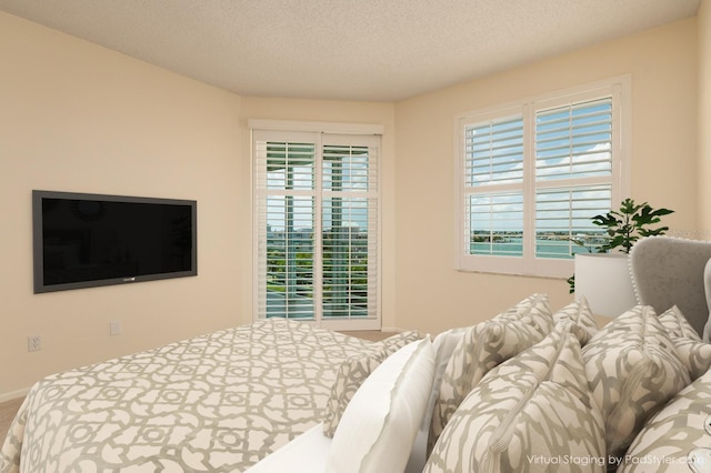 bedroom featuring multiple windows, carpet, and a textured ceiling