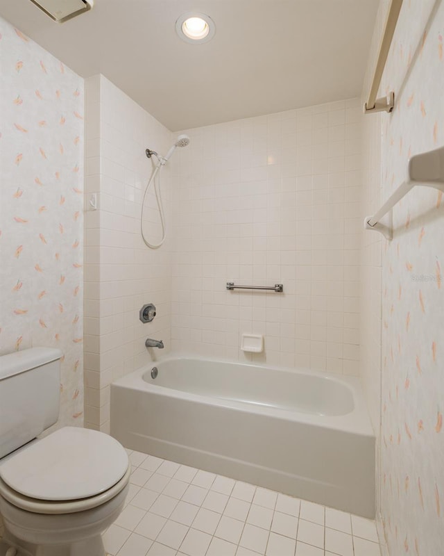 bathroom featuring tile patterned flooring, tiled shower / bath, and toilet