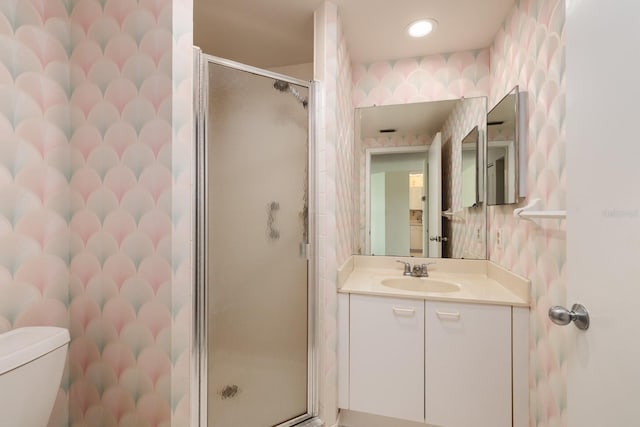 bathroom featuring toilet, a shower with shower door, and vanity