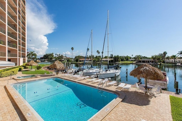 view of swimming pool featuring a boat dock, a patio, and a water view