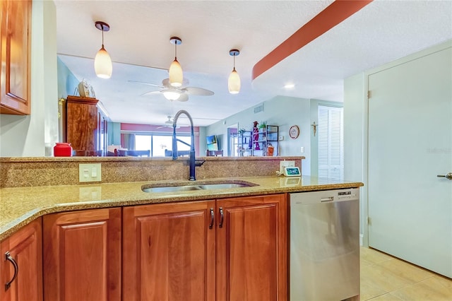 kitchen featuring pendant lighting, dishwasher, sink, light tile patterned floors, and light stone counters