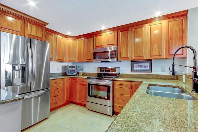 kitchen featuring light tile patterned floors, stainless steel appliances, light stone counters, and sink