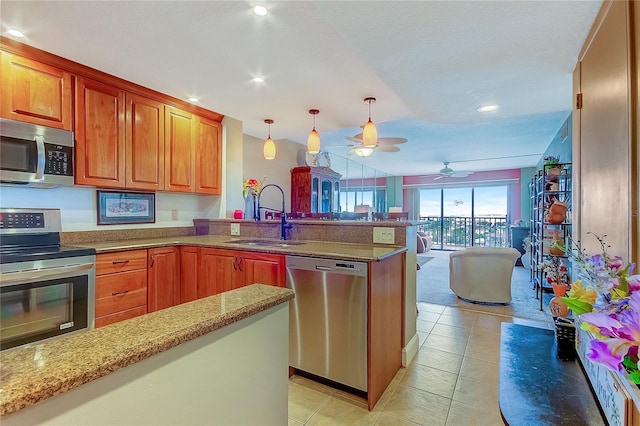 kitchen with appliances with stainless steel finishes, ceiling fan, sink, light tile patterned floors, and decorative light fixtures