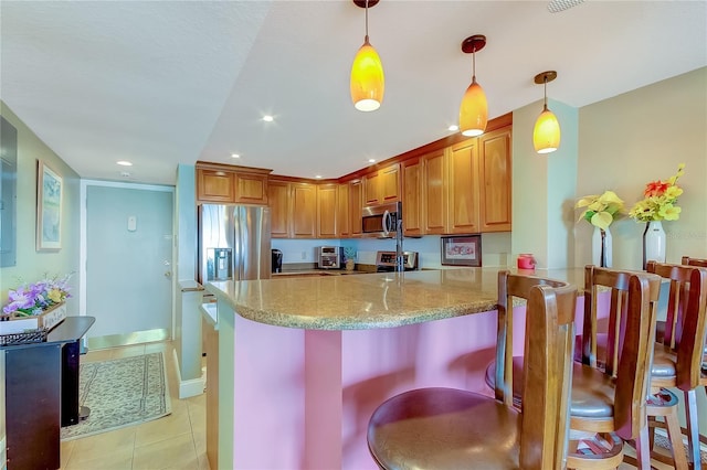 kitchen with stainless steel appliances, light stone counters, kitchen peninsula, decorative light fixtures, and light tile patterned floors