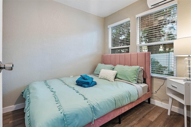 bedroom with a wall mounted AC and dark wood-type flooring