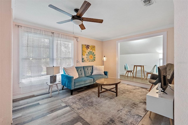 living room with hardwood / wood-style flooring, ceiling fan, and ornamental molding