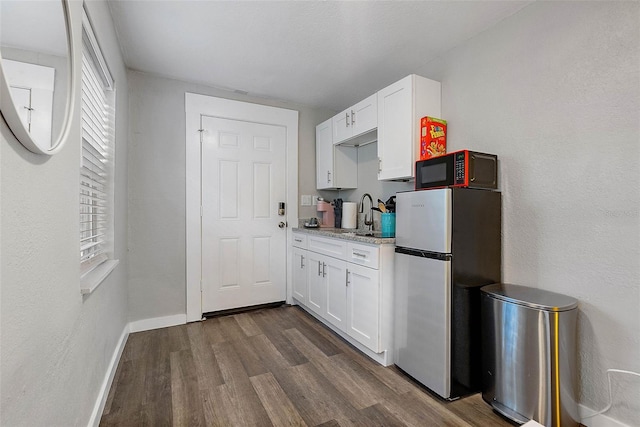 kitchen featuring white cabinets, stainless steel refrigerator, dark wood-type flooring, and sink