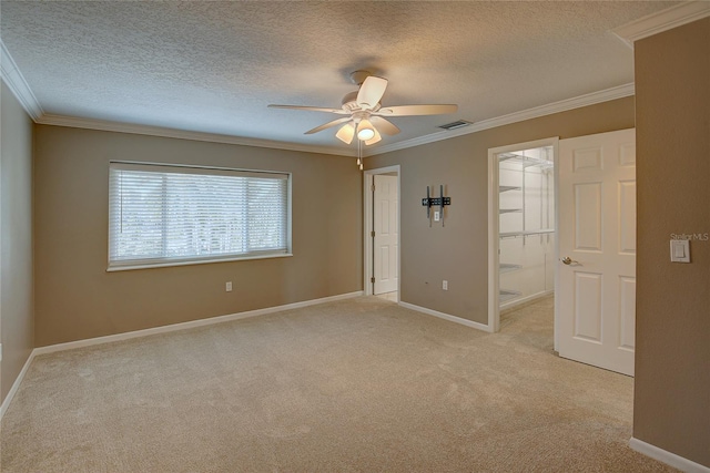 empty room with light colored carpet, a ceiling fan, crown molding, and baseboards