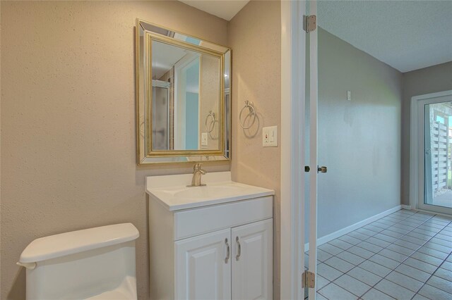 bathroom featuring baseboards, toilet, vanity, and tile patterned flooring