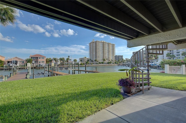 view of community featuring a water view, a boat dock, and a yard