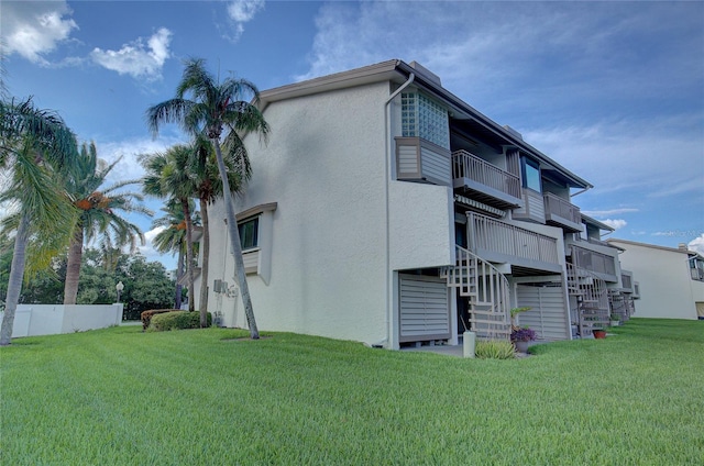 view of side of property with a balcony and a lawn