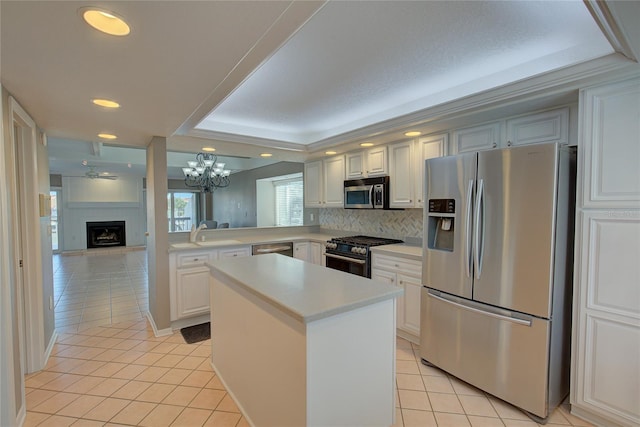 kitchen featuring a sink, stainless steel appliances, a large fireplace, light countertops, and light tile patterned floors