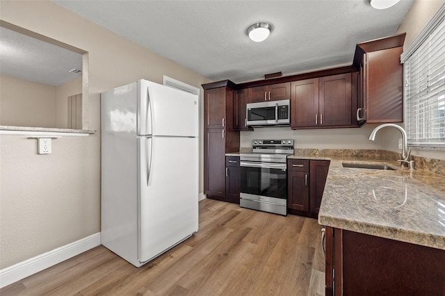 kitchen with dark brown cabinetry, sink, a textured ceiling, light wood-type flooring, and appliances with stainless steel finishes