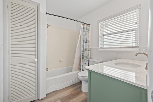 full bathroom with shower / bath combo, tile walls, vanity, wood-type flooring, and toilet