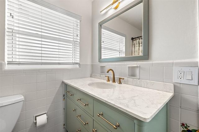 bathroom featuring vanity, tile walls, and toilet