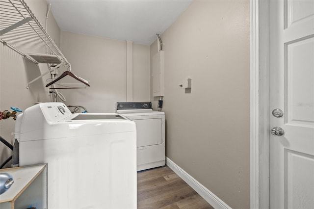 washroom featuring electric panel, washer and clothes dryer, sink, and light hardwood / wood-style flooring