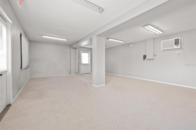 basement with light colored carpet, a wall mounted air conditioner, and a textured ceiling