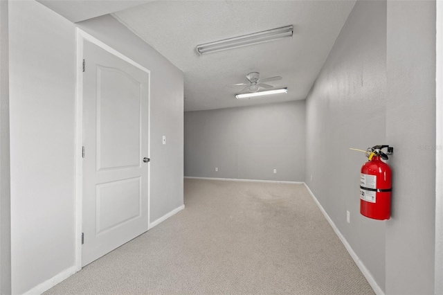 empty room with ceiling fan, light carpet, and a textured ceiling