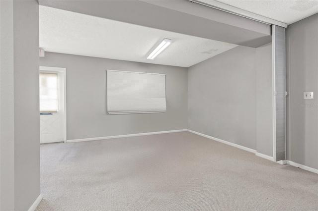 spare room featuring light carpet and a textured ceiling