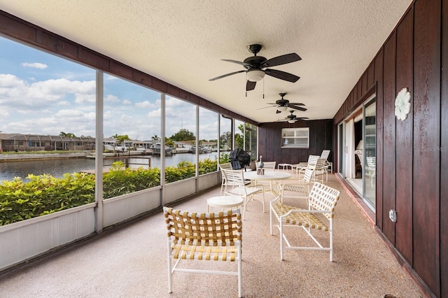 unfurnished sunroom featuring a water view and ceiling fan