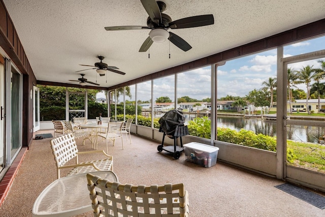 sunroom with plenty of natural light, ceiling fan, and a water view