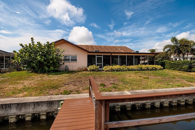 back of house featuring a sunroom, a yard, and a water view