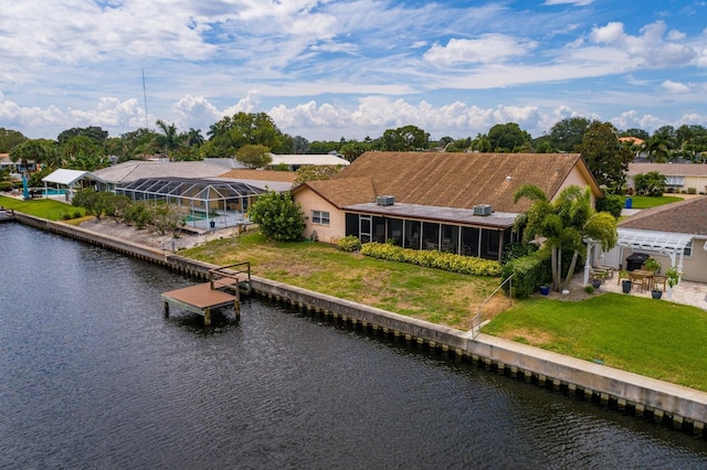 rear view of property featuring a sunroom, a water view, and a lawn