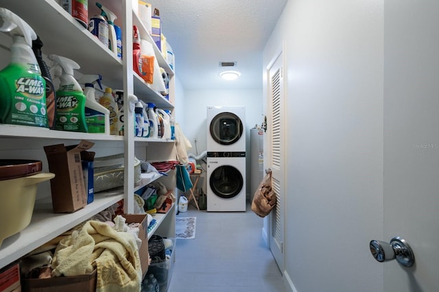 laundry room with stacked washing maching and dryer and a textured ceiling