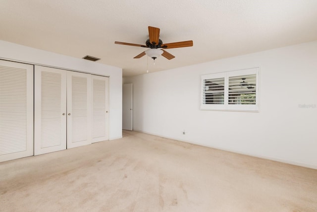 unfurnished bedroom featuring ceiling fan, a closet, and light colored carpet