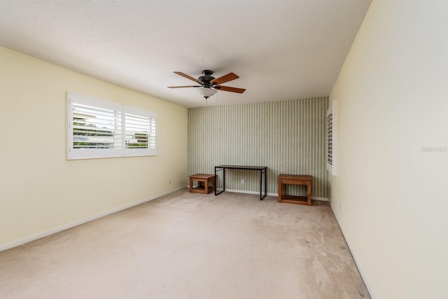 spare room with light carpet, ceiling fan, and a textured ceiling