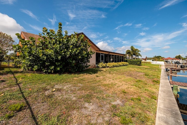 view of yard featuring a sunroom and a boat dock