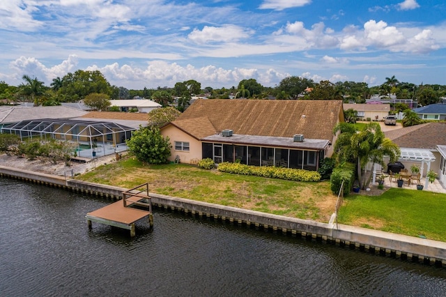 rear view of house featuring a sunroom, a yard, and a water view