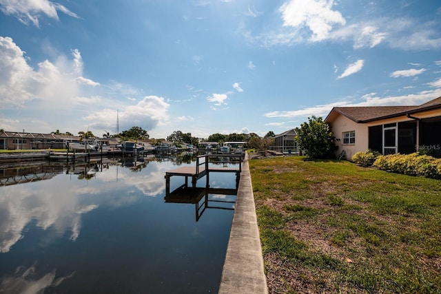 view of dock with a lawn, a water view, and boat lift