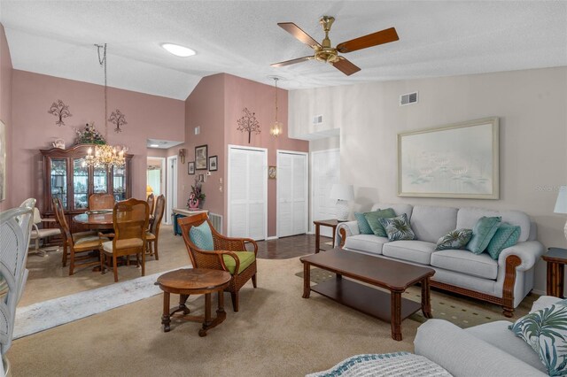 carpeted living room with ceiling fan with notable chandelier, lofted ceiling, and a textured ceiling