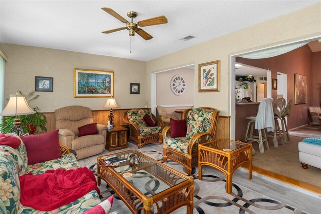 living room featuring ceiling fan, a textured ceiling, and light hardwood / wood-style flooring