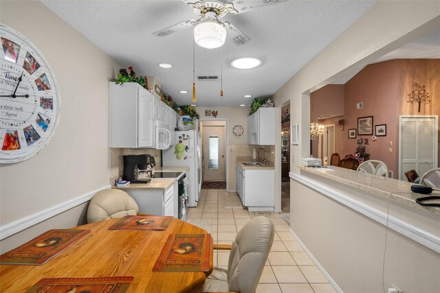 kitchen featuring white cabinets, sink, ceiling fan, light tile patterned floors, and a textured ceiling