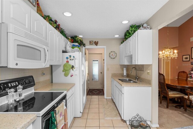 kitchen featuring light tile patterned floors, white appliances, white cabinetry, and sink