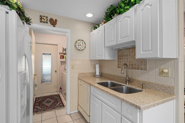 kitchen with white appliances, sink, light stone countertops, light tile patterned floors, and white cabinetry