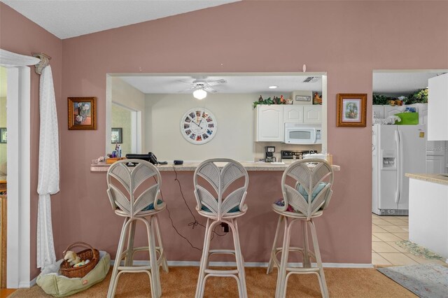 kitchen with white appliances, white cabinets, vaulted ceiling, ceiling fan, and light tile patterned floors