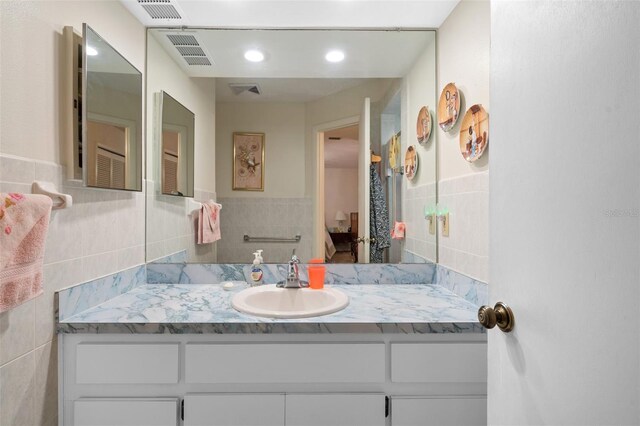 bathroom featuring vanity and tile walls