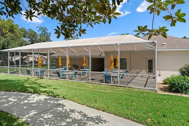 rear view of property featuring glass enclosure, a yard, and a patio