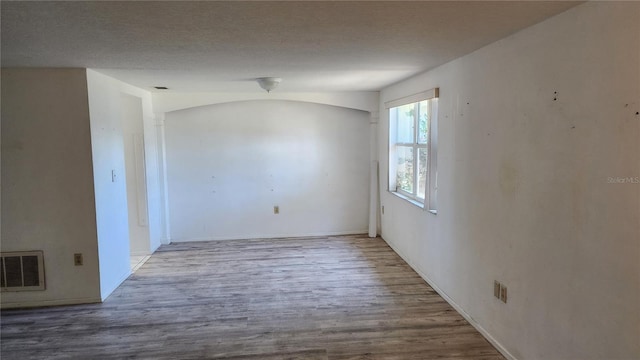 unfurnished room with hardwood / wood-style floors and lofted ceiling