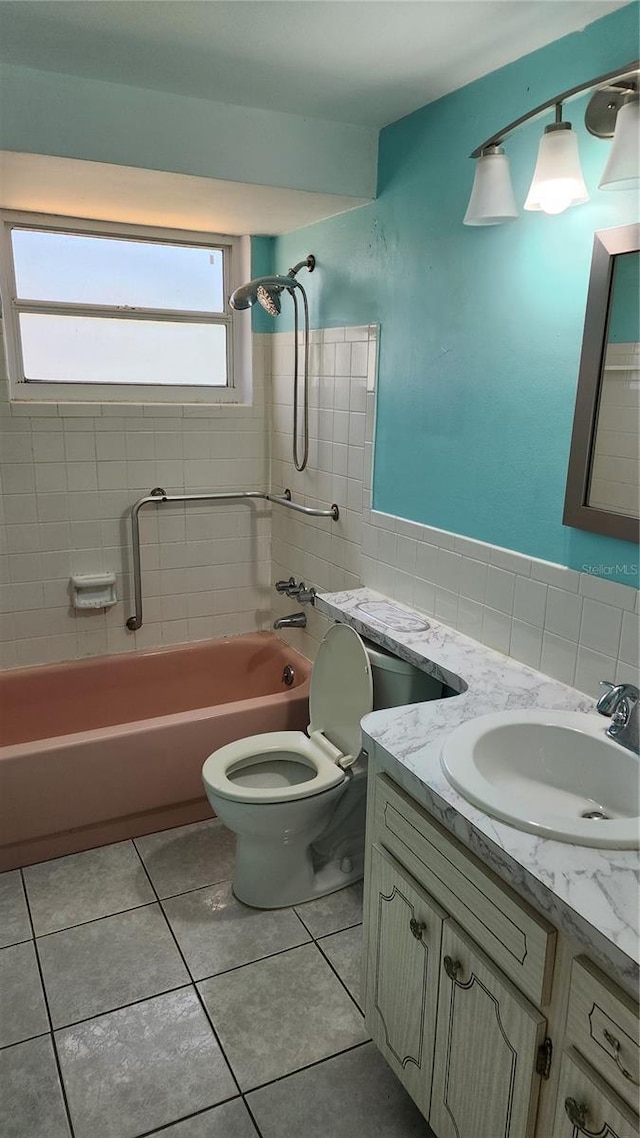 full bathroom featuring toilet, vanity, tile patterned flooring, tile walls, and tiled shower / bath combo