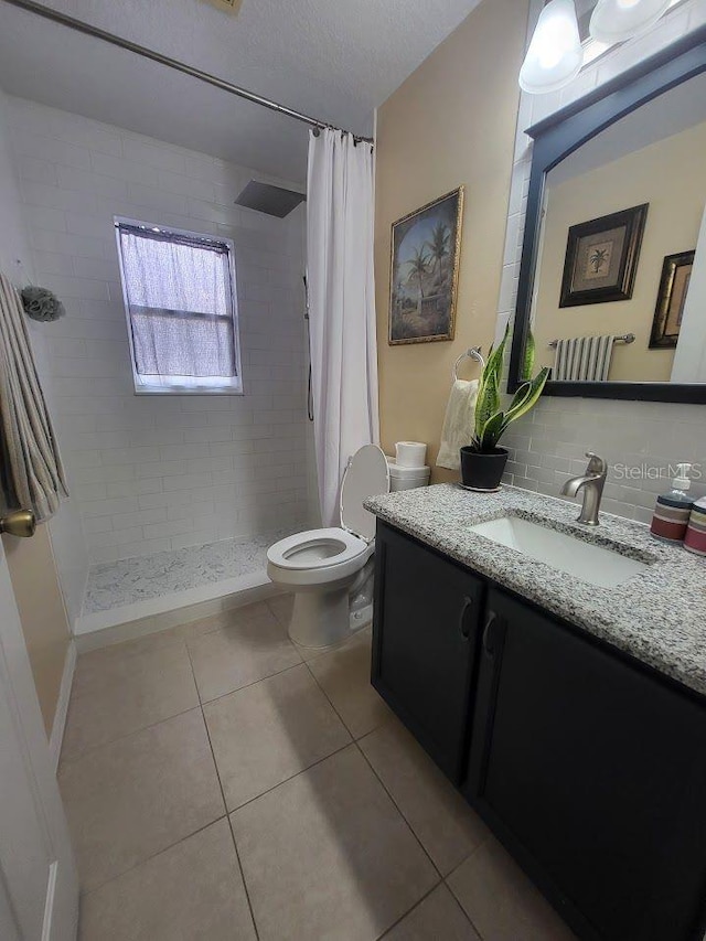 bathroom with tile patterned flooring, backsplash, walk in shower, vanity, and toilet