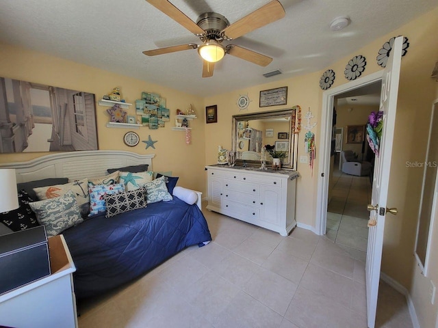 tiled bedroom with ceiling fan and a textured ceiling