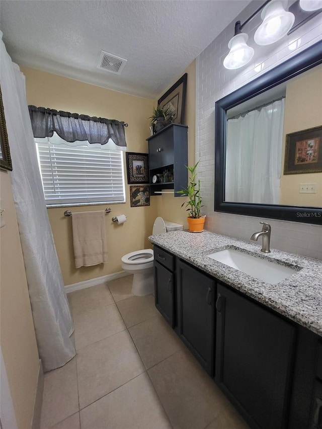 bathroom with vanity, toilet, a textured ceiling, and tile patterned floors